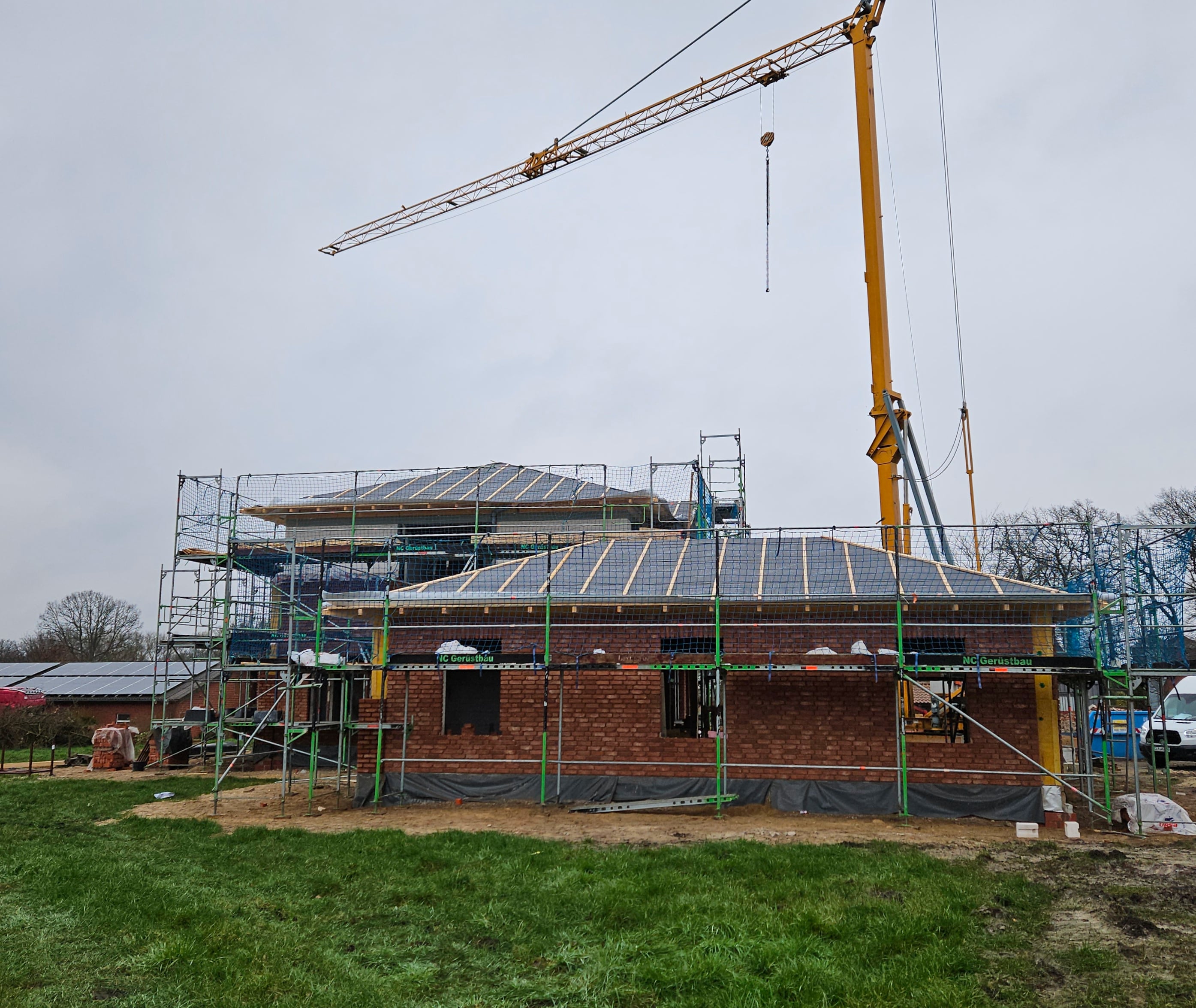 Ein Neubau ohne Dachziegel mit einem Krahn im Hintergrund.