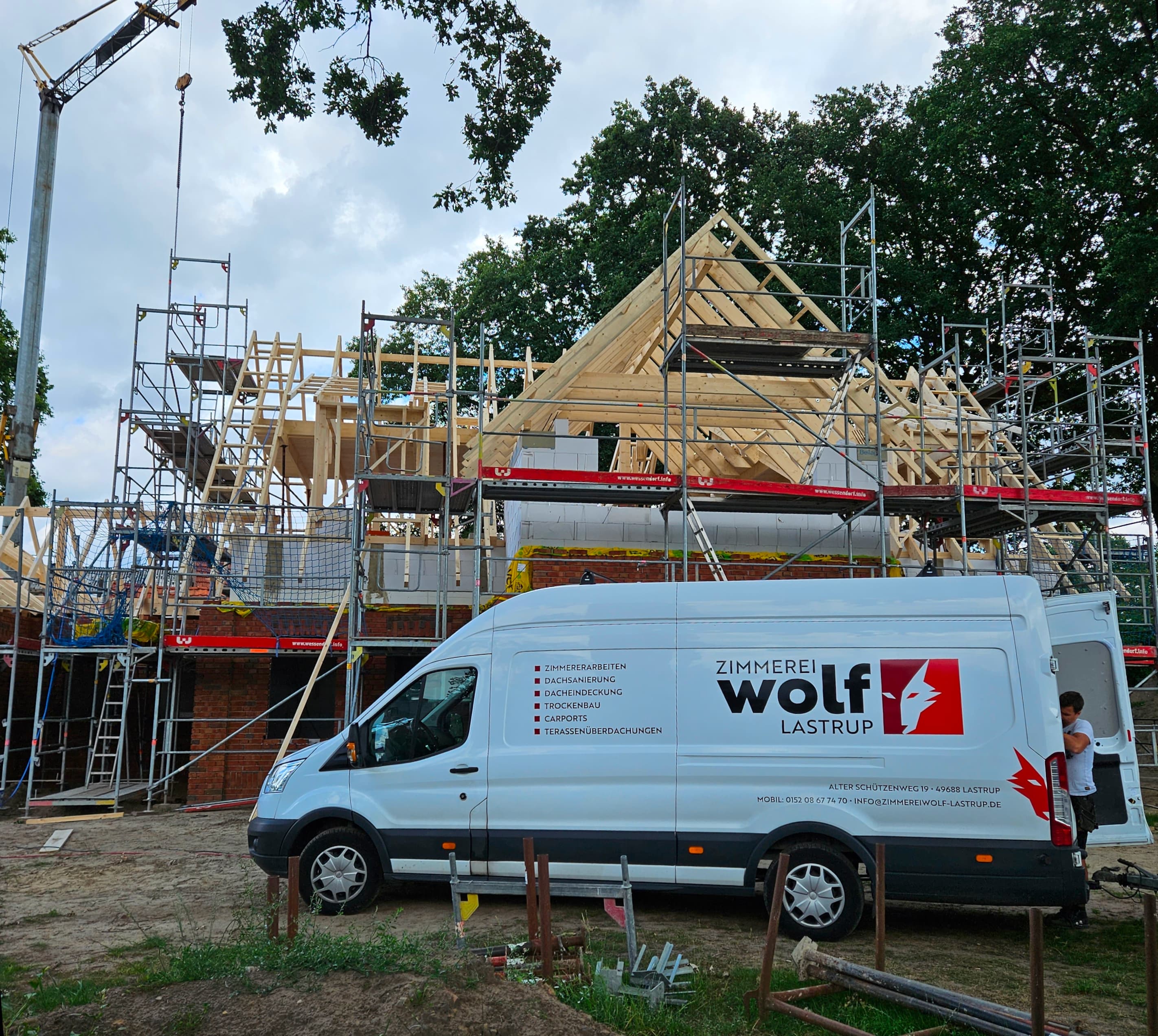 Ein Transporter, der vor einem im Bau befindlichen Neubau steht.